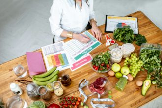 Writing a diet plan on the table full of healthy food